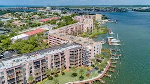 Un hotel moderno con múltiples balcones, una marina con barcos y vista al río.