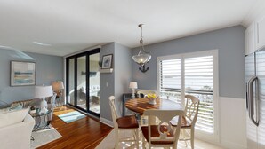 Un comedor con una mesa y sillas de madera, una araña y vistas amplias a través de puertas de vidrio.