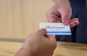 A person holding a welcome card with "Welcome! Enjoy your stay!" and "Key Card" text. - Mare Blue & Suites (Apokoronas)