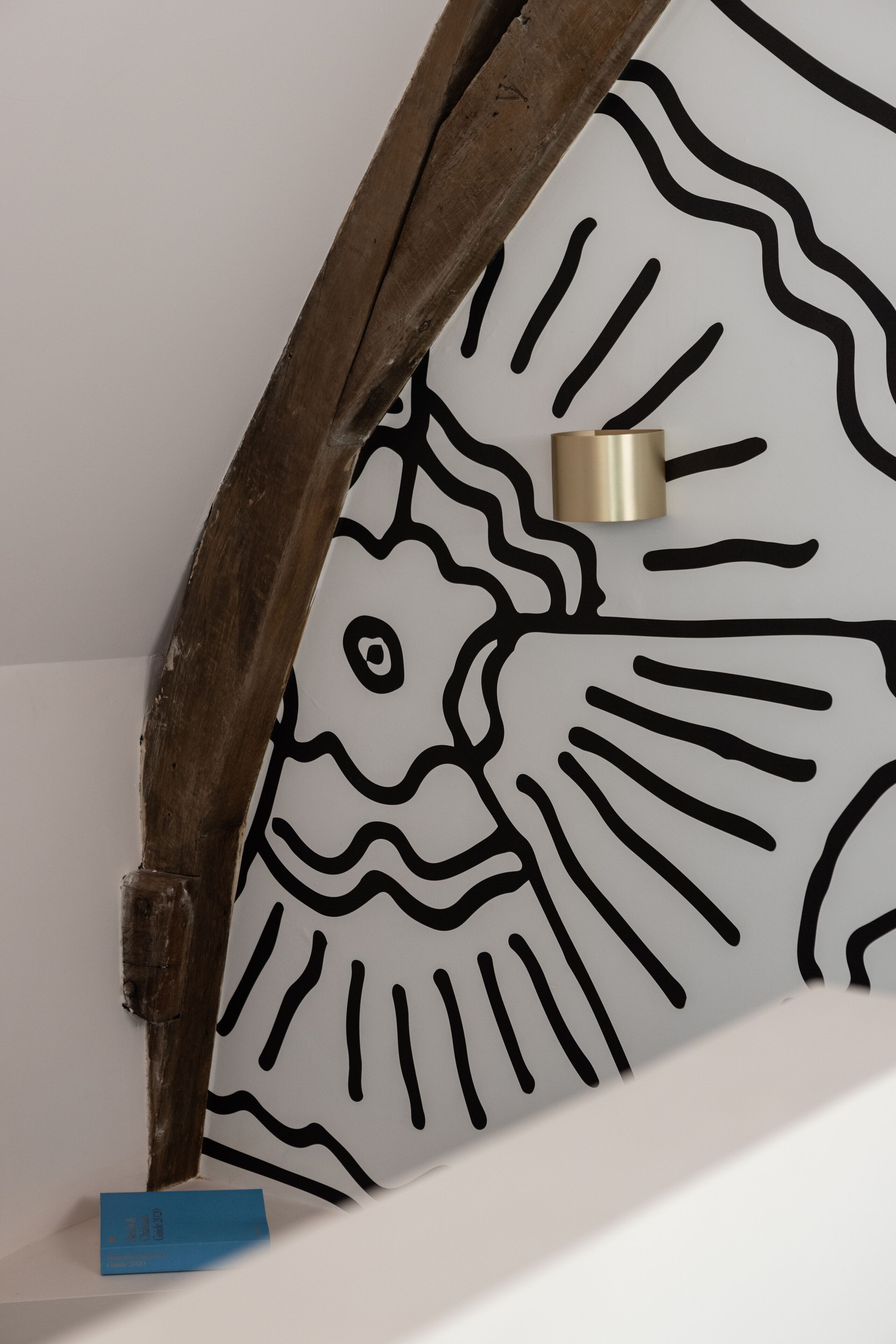 A wooden beam and a wall with a black and white abstract design.