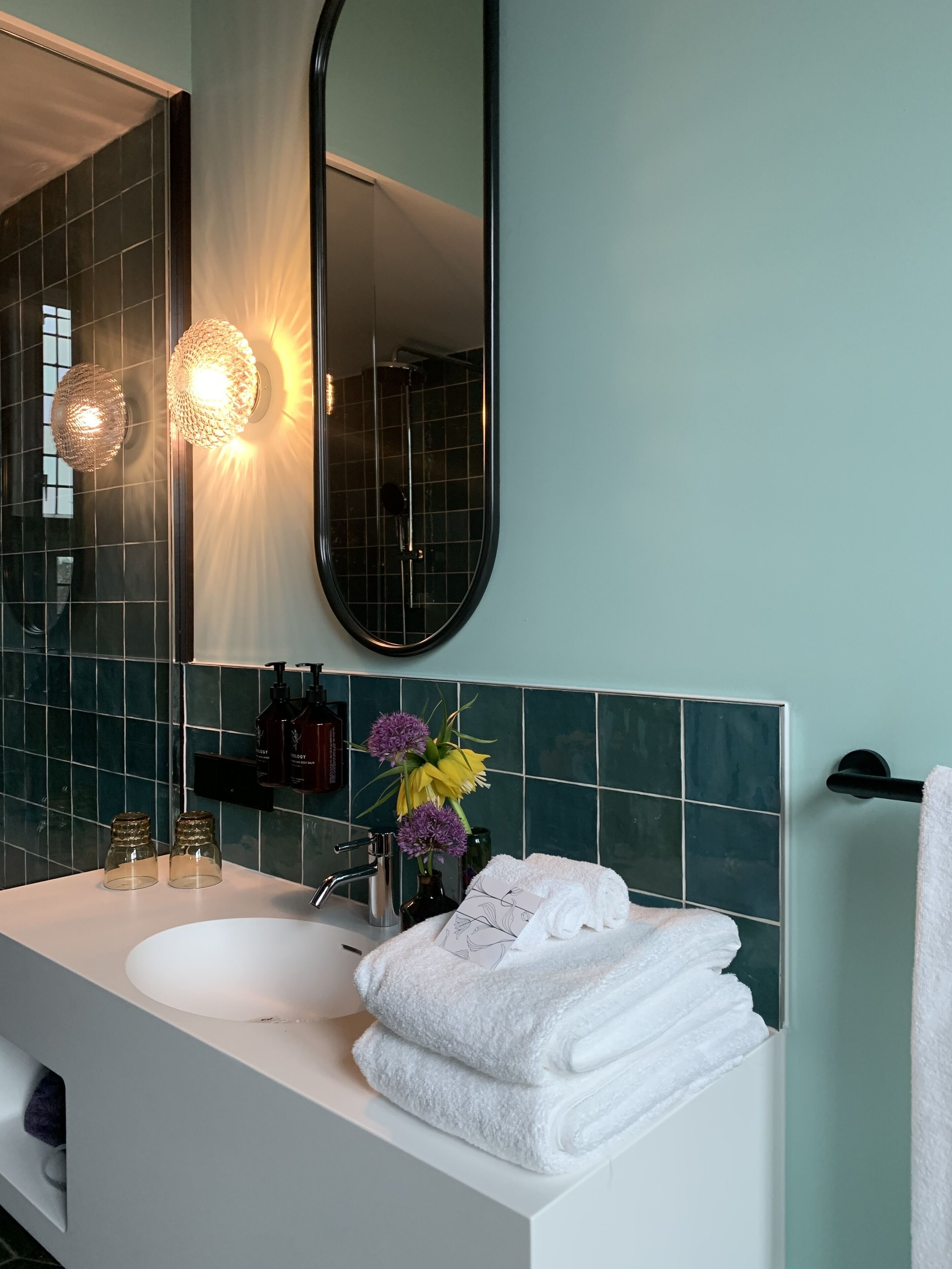 A bathroom with a white sink, a mirror, and a towel rack.