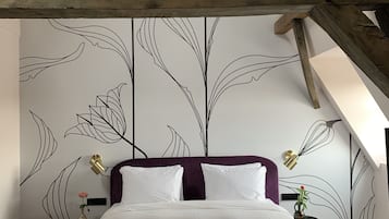 Quarto com cama, mesa de cabeceira, luminária na parede e parede decorativa com padrões de folhas.
