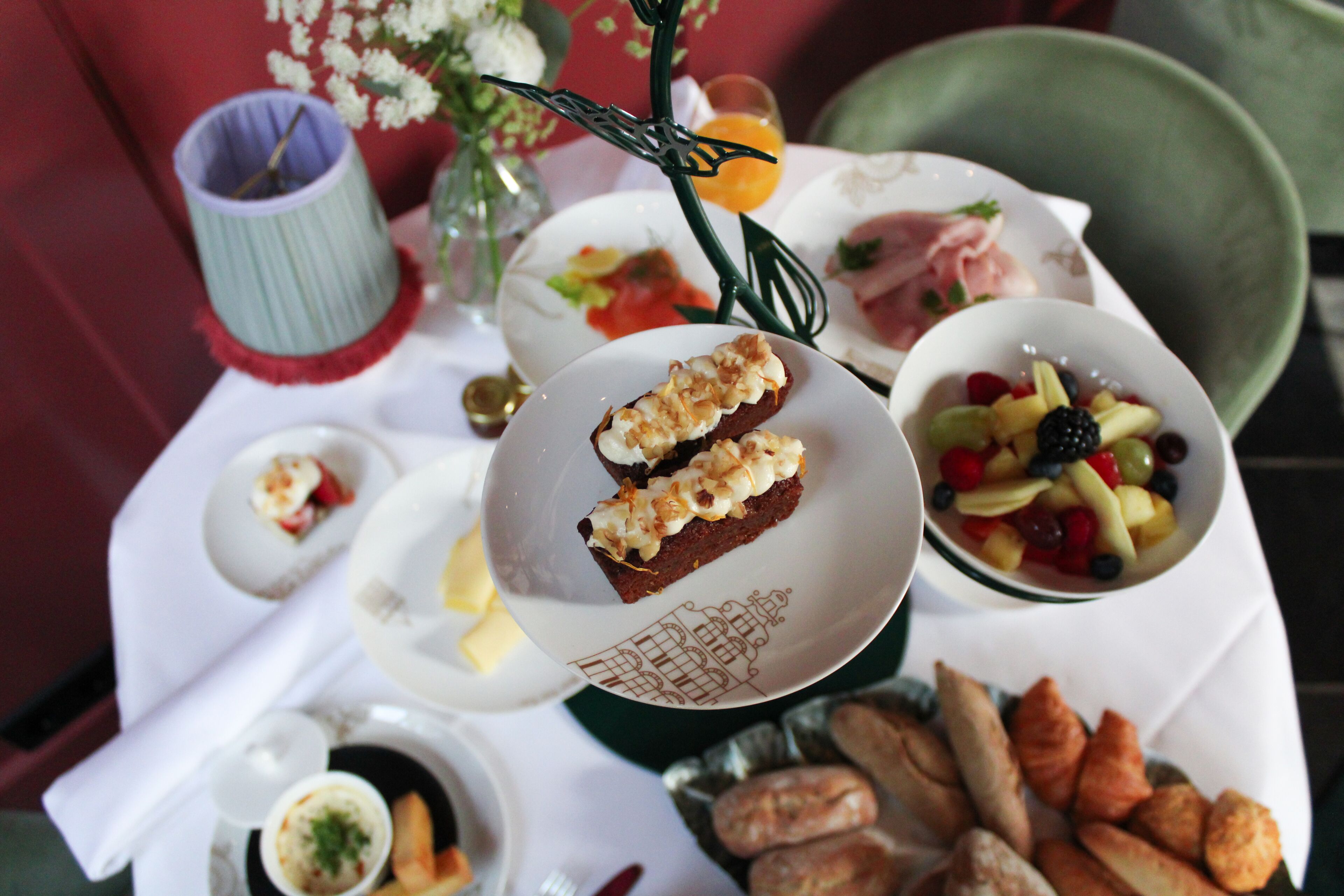 A table set with various dishes including a fruit bowl, a plate with a pastry, and a small bowl of soup.
