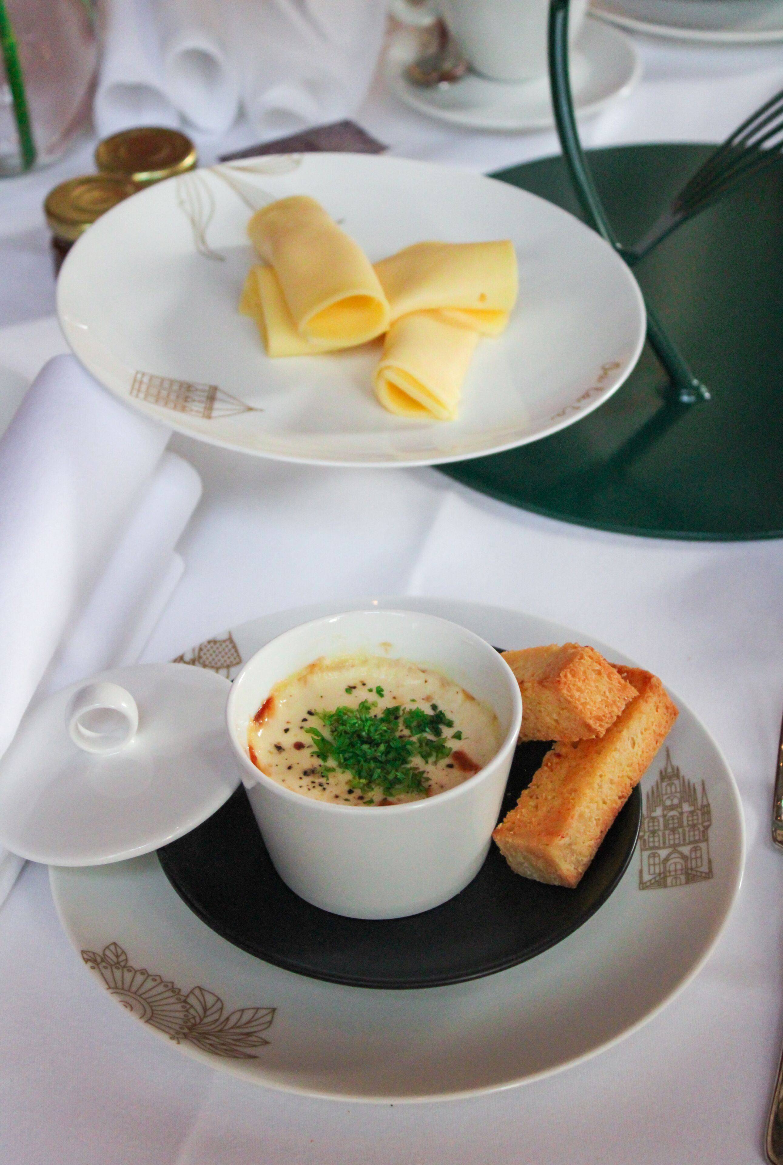 Ein gedeckter Tisch mit einer Platte gefüllter Crêpes, einer Suppe, garniert mit Kräutern, und einem Stück Brot.