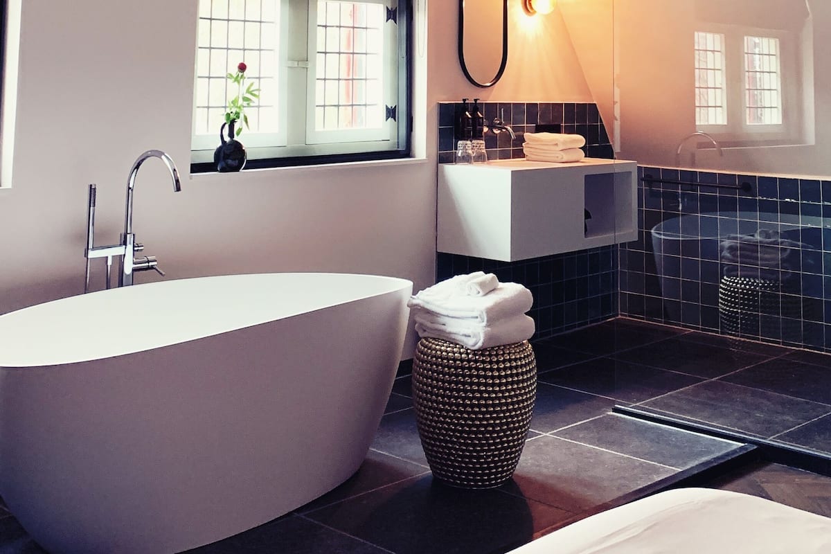 A modern bathroom with a freestanding bathtub, a vanity with a mirror, and a window with a view.