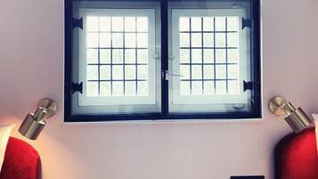 A room with a large window, two small round tables, and a bed.