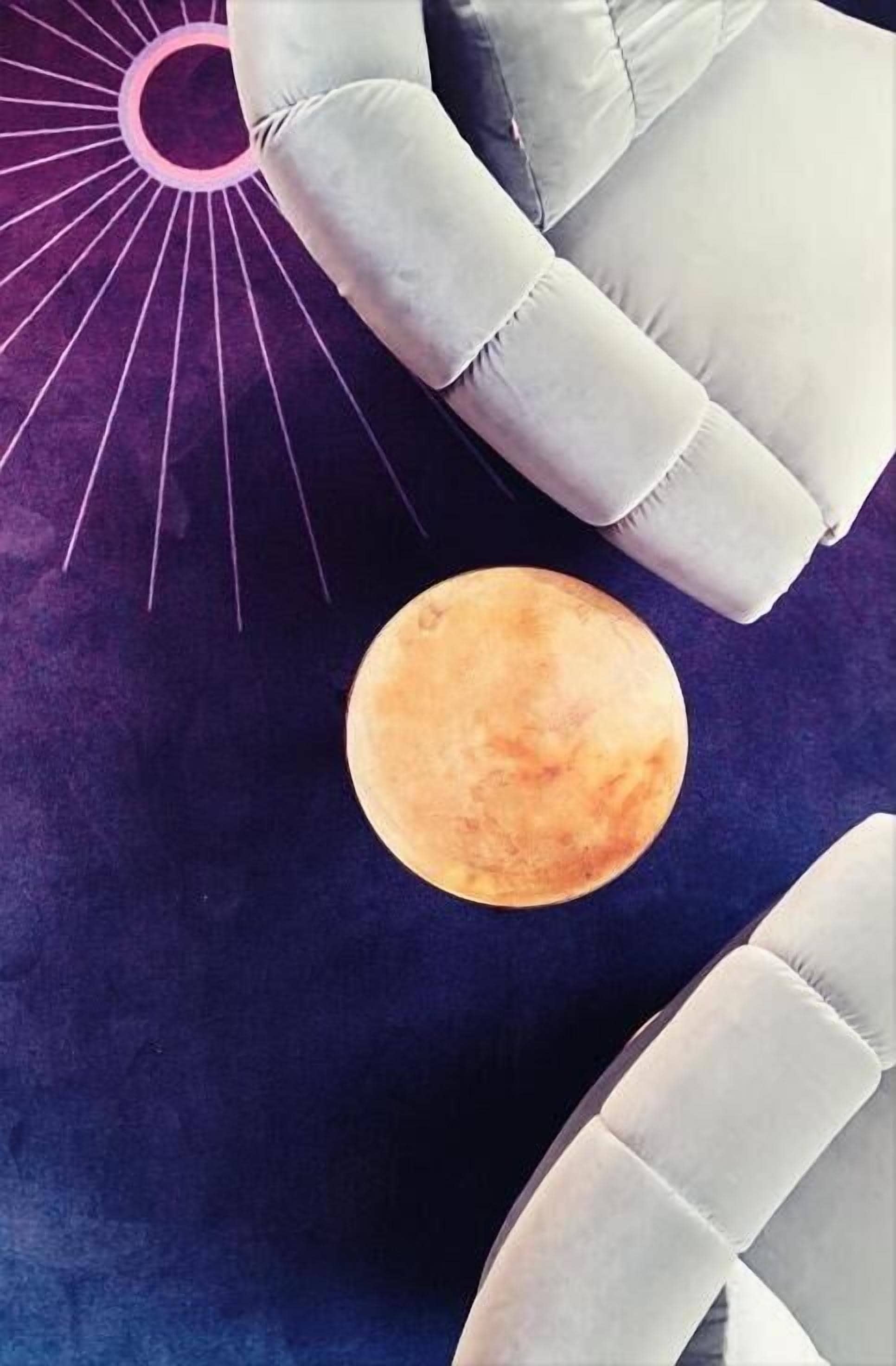 A room with a large, round, orange moon-like object on a dark blue background, a white cushioned chair, and a purple sun-like design.