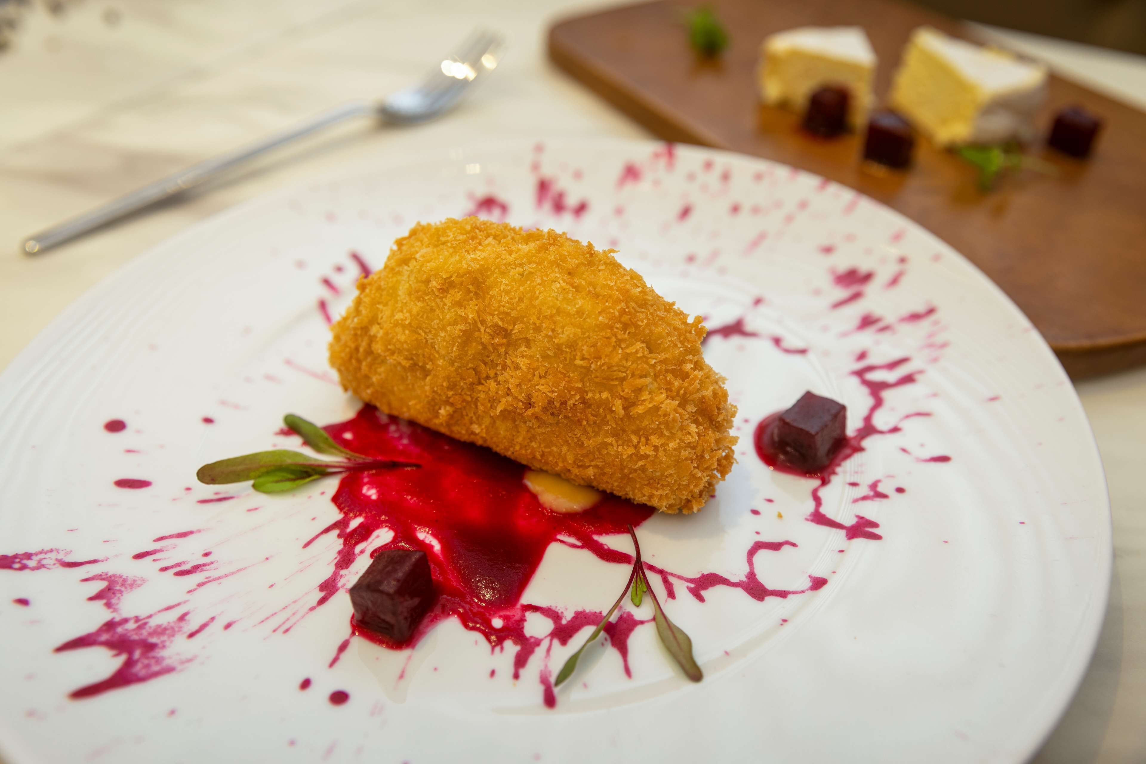 Un plato con un ingrediente enharinado, salsa roja y trozos de chocolate.