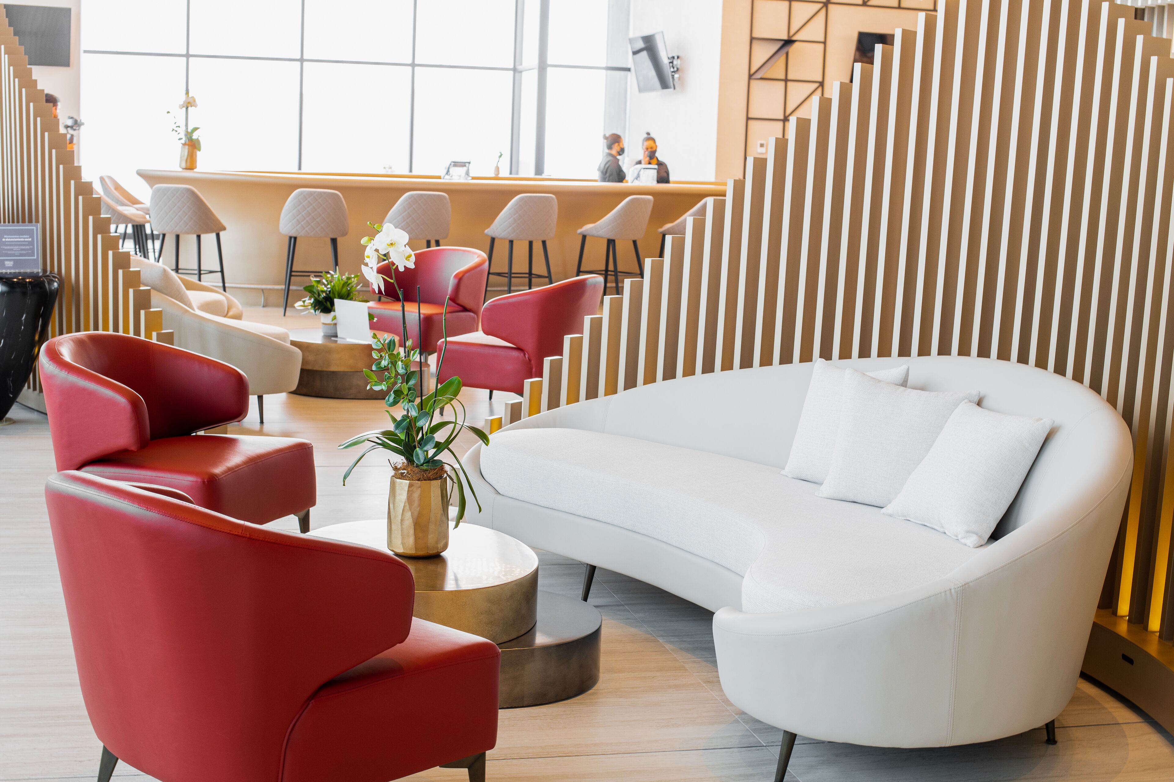 A modern lobby with a white sofa, red chairs, and a reception desk.