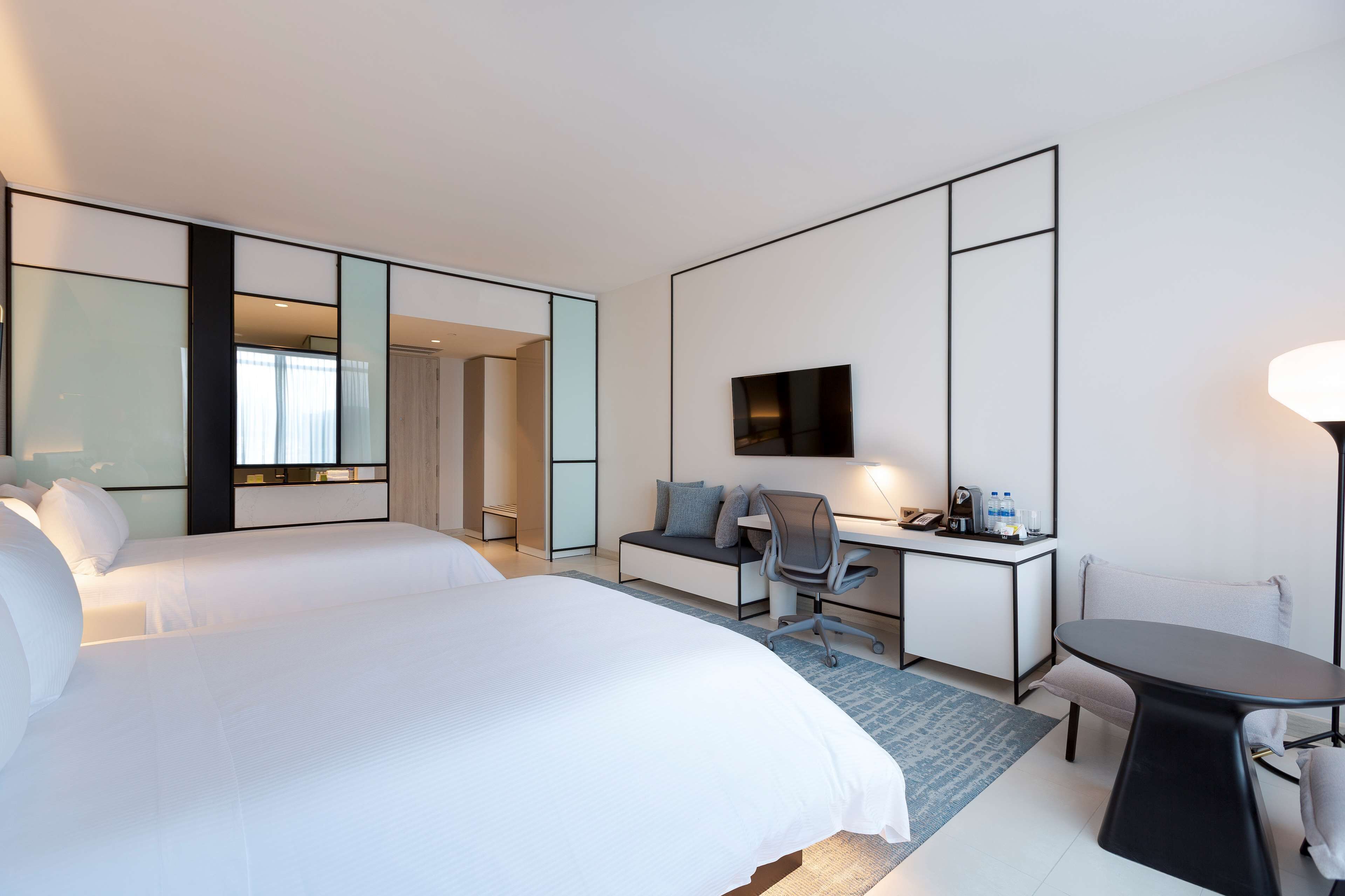 Una habitación de hotel con una cama grande, un escritorio con una silla, un televisor y una mesita.
