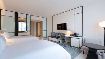 Una habitación de hotel con una cama grande, un escritorio con una silla, un televisor y una mesita.