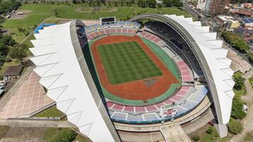Vista aérea de un estadio con una amplia zona de asientos, un campo central y zonas verdes circundantes.