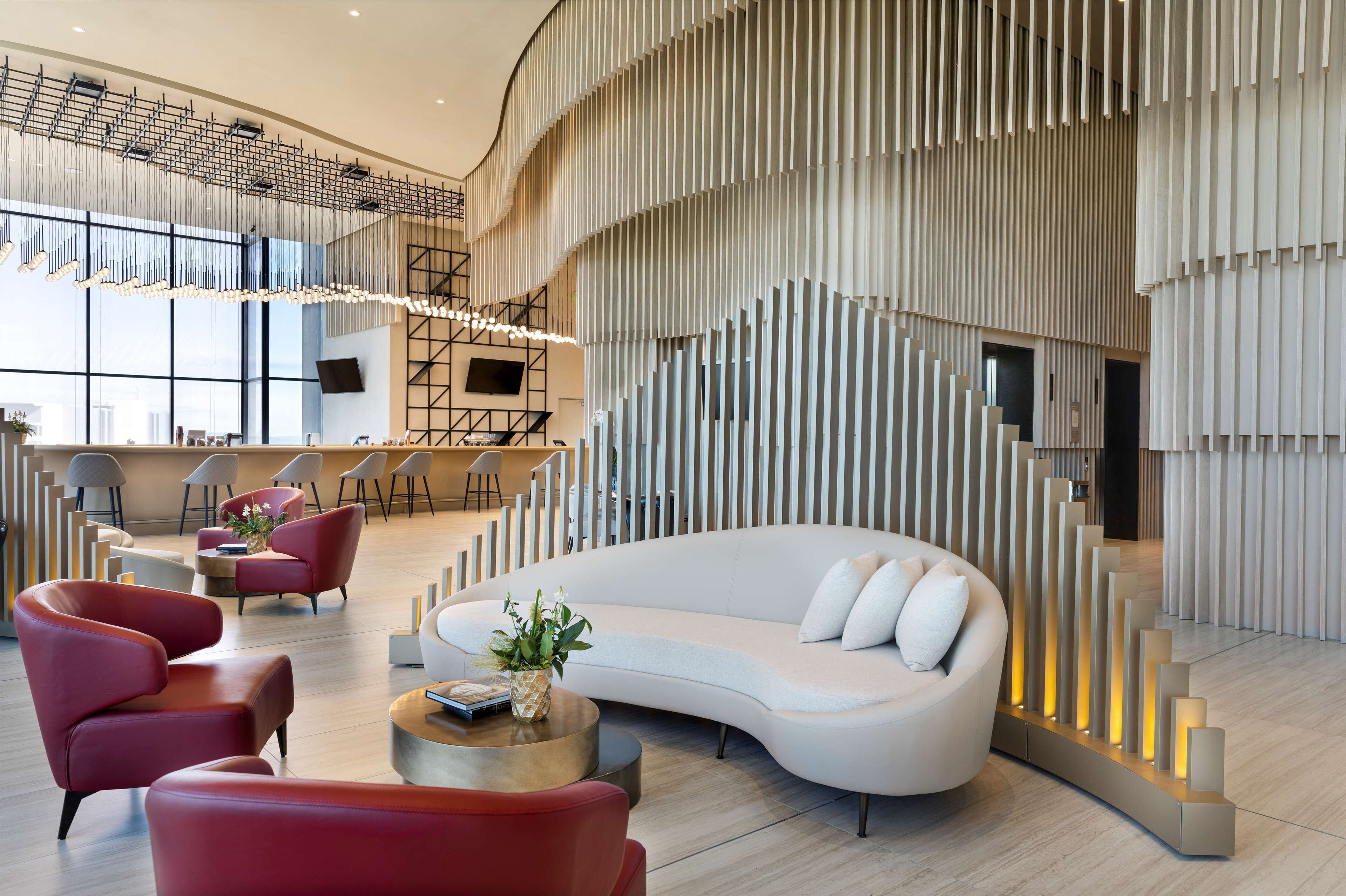 A modern lobby with a curved white sofa, red chairs, and a reception desk.