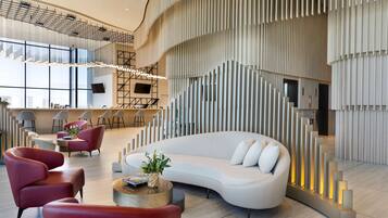 A modern lobby with a curved white sofa, red chairs, and a reception desk.