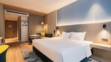 A modern hotel room with a large bed, bedside tables, a desk, and a chair.