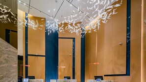 En moderne lobby med marmorerede receptiondiske, en blå accentvæg og hængende, løvlignende dekorationer.