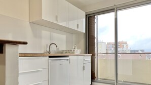 Een moderne keuken met witte kasten, een vaatwasser en een grote schuifglazen deur naar een balkon.
