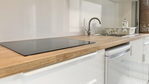 Een moderne keuken met een houten aanrecht, witte kasten, een zwart snijplank en een roestvrijstalen spoelbak.