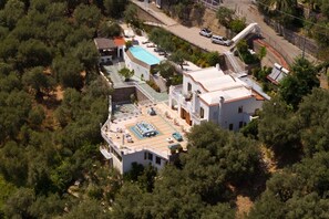 Vista aérea de una propiedad con piscina, varias edificaciones y árboles circundantes.