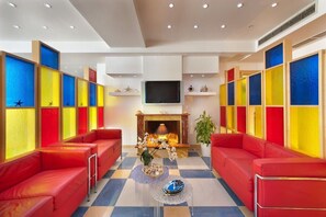 Un hall de hotel con asientos rojos, chimenea y paredes coloridas.