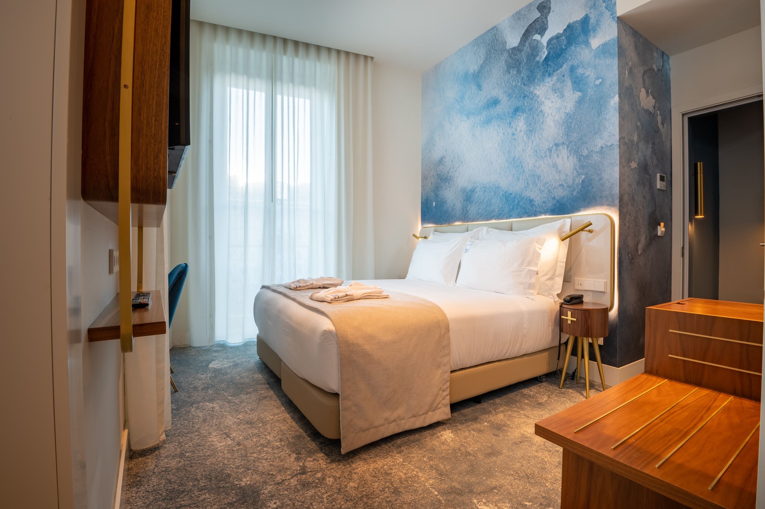 Une chambre d’hôtel avec un lit, une table de chevet et un grand tableau abstrait accroché au mur.