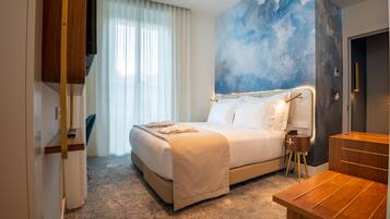 Une chambre d’hôtel avec un lit, une table de chevet et un grand tableau abstrait accroché au mur.