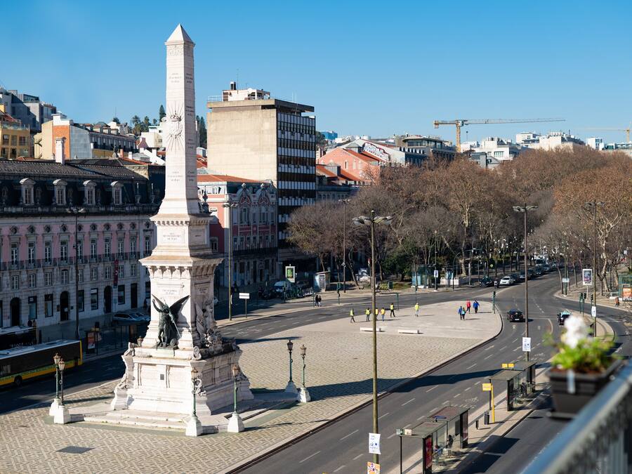 Ein Stadtplatz mit einem Denkmal, Gebäuden und blauem Himmel.