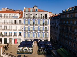 A multi-story building with balconies, a restaurant named 'Pinocchio', and outdoor seating with umbrellas.