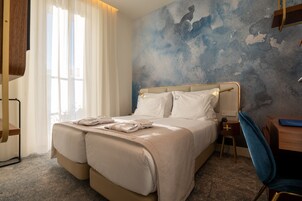 A hotel room with a large bed, a desk, and a chair.