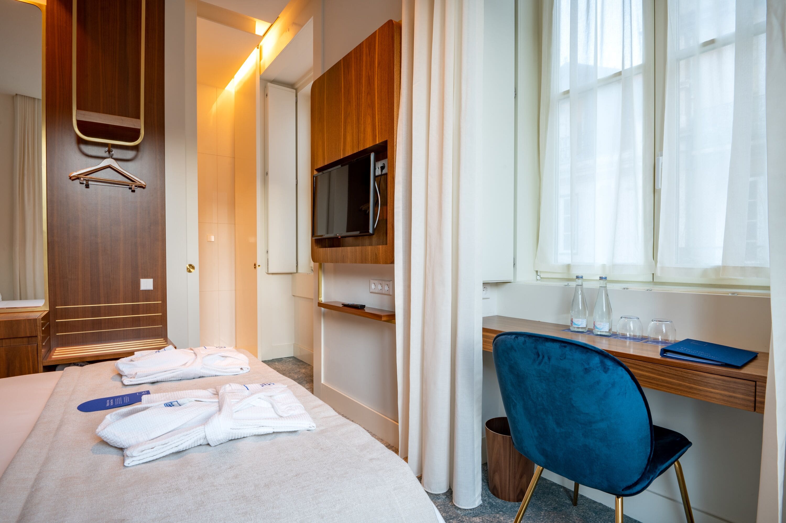Ein Hotelzimmer mit Bett, Schreibtisch, Fernseher und einem Fenster mit Vorhängen.