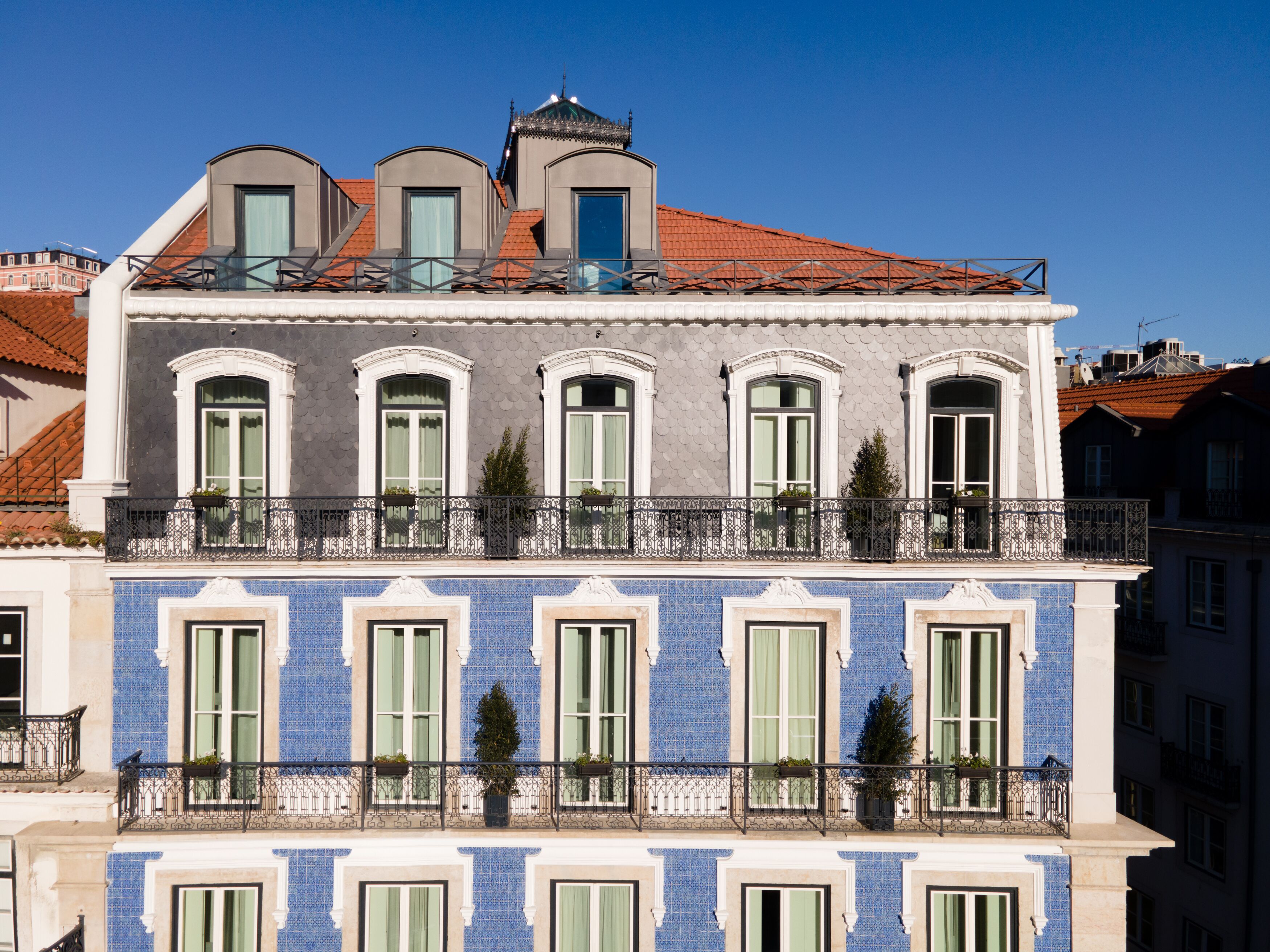 Ein mehrstöckiges Gebäude mit Balkon, großen Fenstern und einer Kachelfassade.