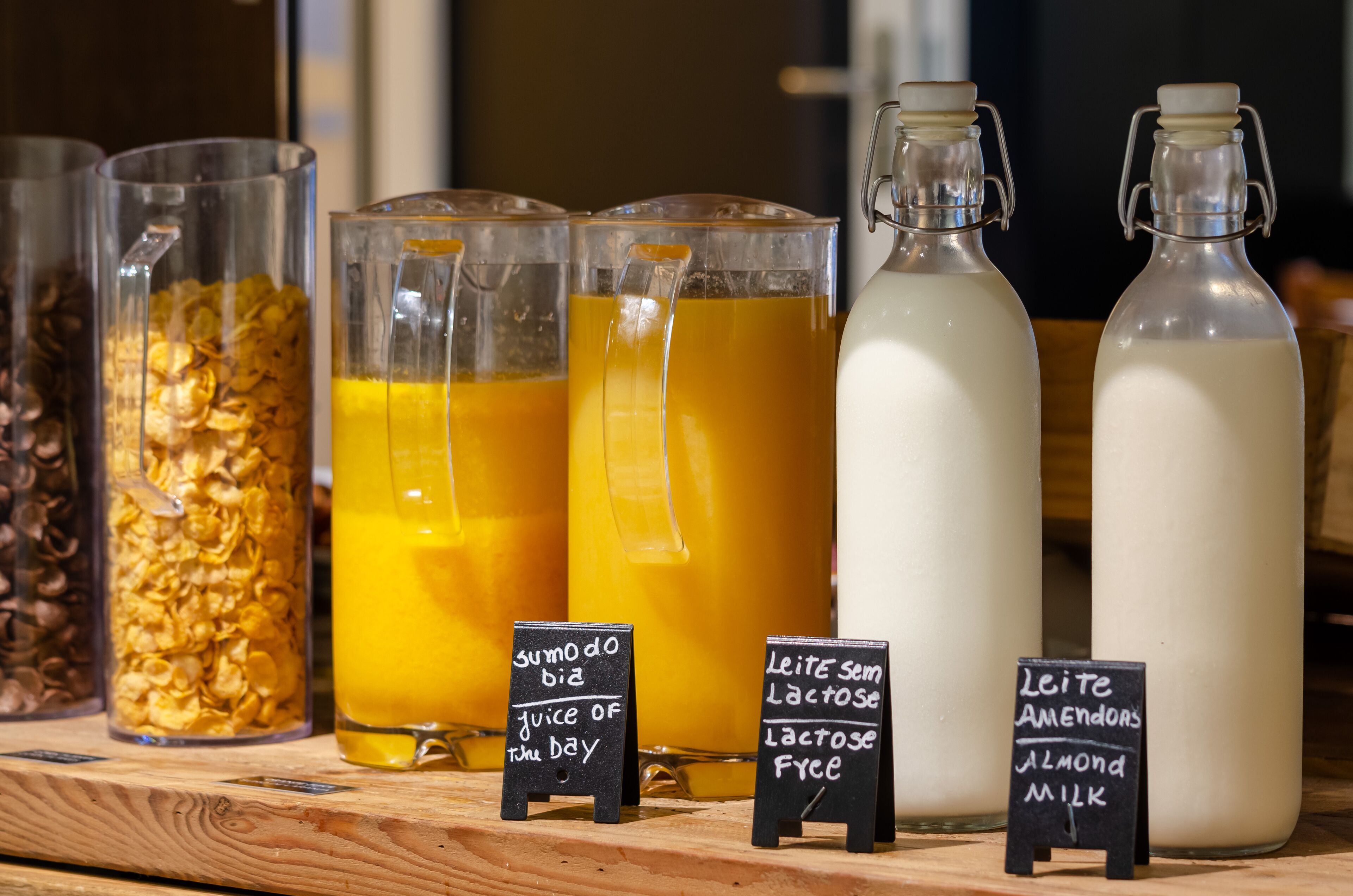 Variedad de bebidas, incluyendo jugo y leche de almendras, con etiquetas que indican su contenido e información nutricional.