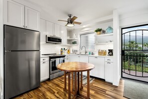 Une cuisine moderne avec des meubles blancs, des appareils en acier inoxydable et une table à manger en bois.