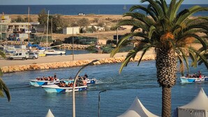 Zona costera con barcos, una palmera y una zona con carpas.