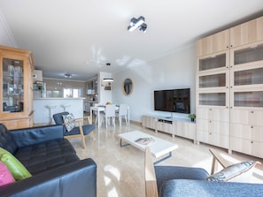 A modern living room with a sofa, coffee table, TV, and built-in shelving. - Mira Baia - Meia Praia Family Apartment (Lagos)