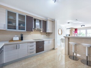 A modern kitchen with a built-in oven, a sink, and a bar area with stools. - Mira Baia - Meia Praia Family Apartment (Lagos)