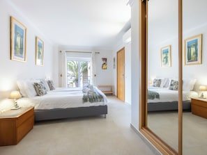 A hotel room with a bed, bedside tables, a mirror, and a balcony with a view. - Mira Baia - Meia Praia Family Apartment (Lagos)