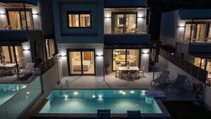 Un edificio moderno de varios pisos con piscina, asientos exteriores y un interior bien iluminado.