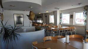 Un comedor con mesas y sillas, una barra blanca y un adorno colgante.