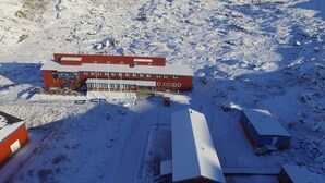 Un edificio grande de color rojo con múltiples ventanas y techo plano, rodeado de nieve.