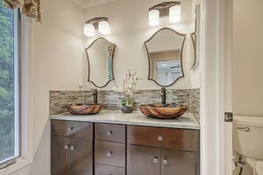 Une salle de bain avec deux lavabos, un mur recouvert de carreaux et une fenêtre.