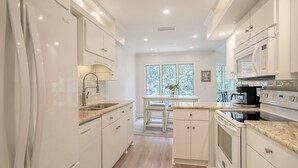 A modern kitchen with white cabinetry, a built-in oven, and a microwave.