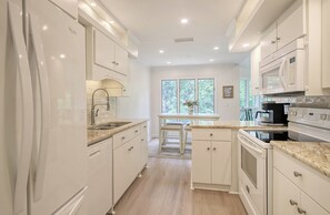 A modern kitchen with white cabinetry, a built-in oven, and a microwave.