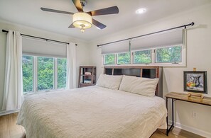 Une chambre avec un grand lit, un ventilateur de plafond et une fenêtre avec des stores.