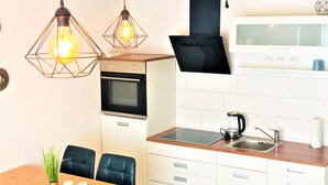 A compact kitchen with a built-in oven, a sink, and a dining area with a table and chairs.