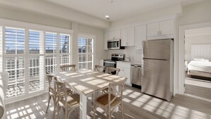 A modern kitchen with white cabinetry, stainless steel appliances, and a dining area with a table and chairs.