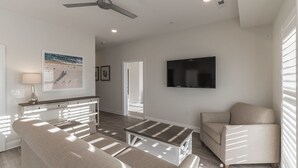 A spacious living room with a sofa, a coffee table, and a TV mounted on the wall.