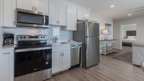 A modern kitchen with white cabinets, stainless steel appliances, and a wooden floor.