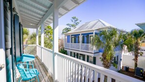 A covered porch with a white railing, a blue table, and chairs. - Seagrove 30A Beach Bungalow with Pool and Hot Tub (Santa Rosa Beach)