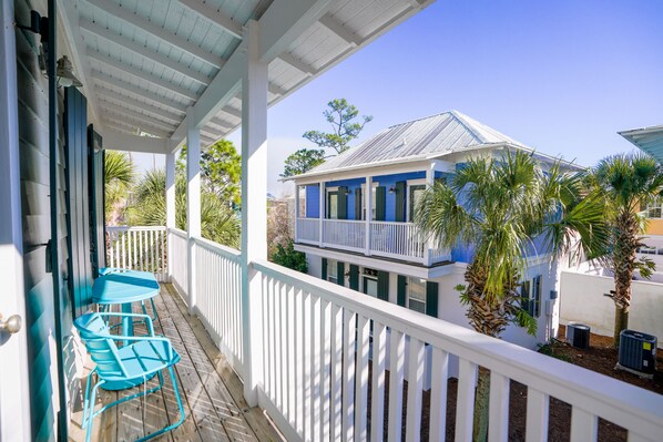 A covered porch with a white railing, a blue table, and chairs.